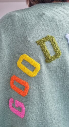 Détail lettres colorées good vibes au dos du gilet femme